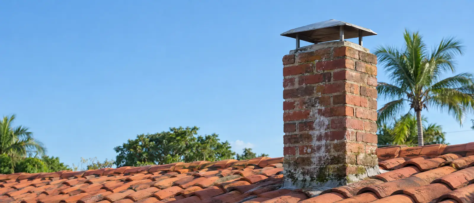Brick chimney with a metal cap on a low-rise home