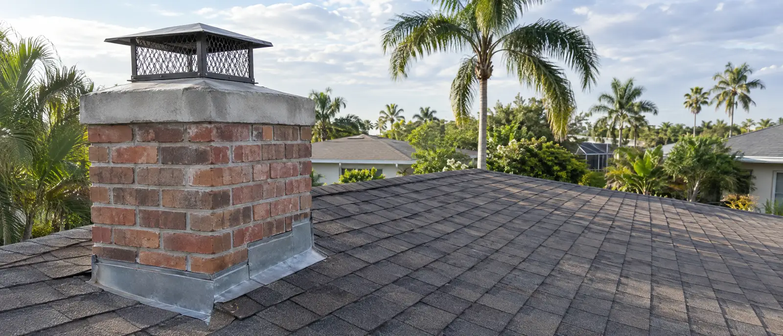Top of a masonry chimney showing the crown, cap and roof flashing